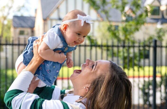 Nanny holding up and smiling at baby