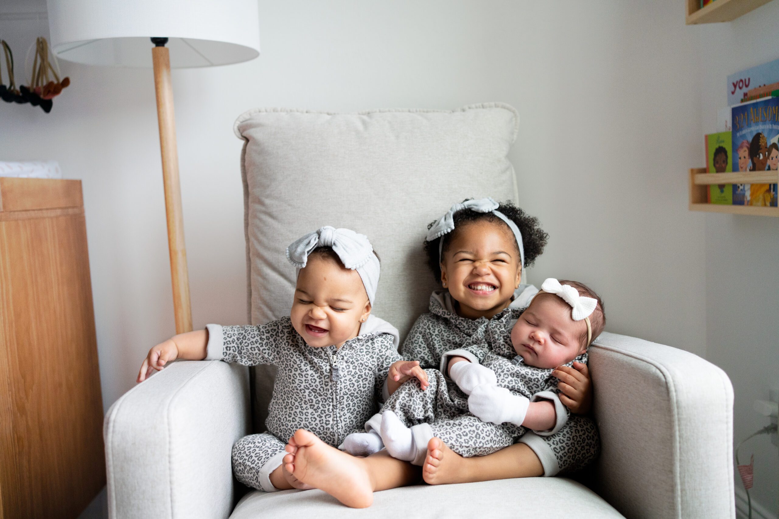 3 siblings sitting in a chair - 2 toddlers and a baby